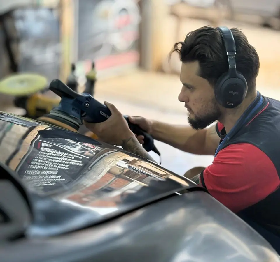Gilberto polindo o capô de um carro escuro