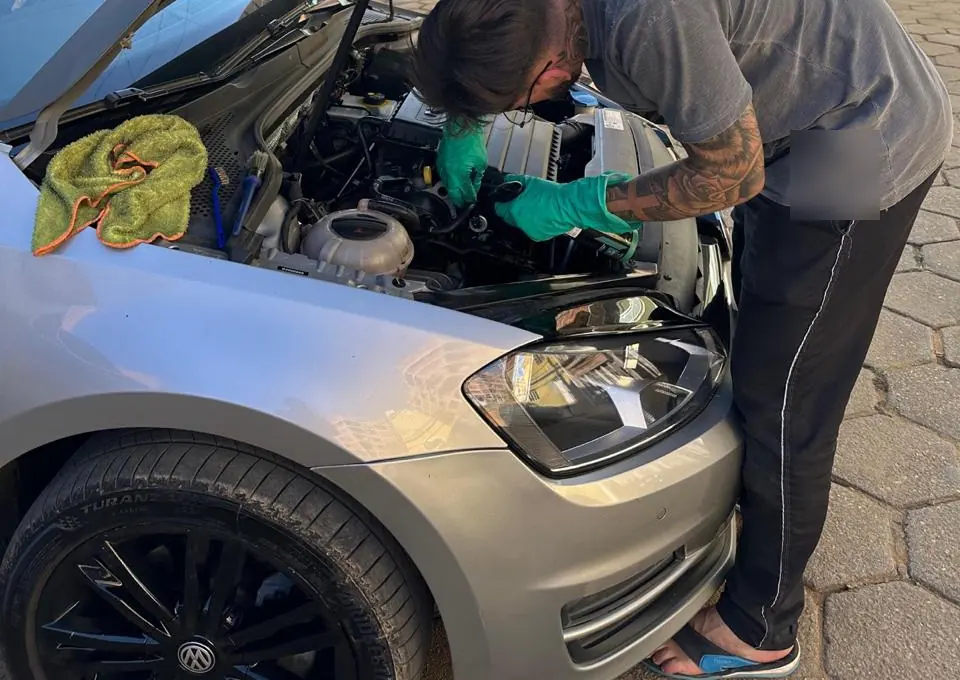 Limpeza do motor de um carro prata com o capô aberto