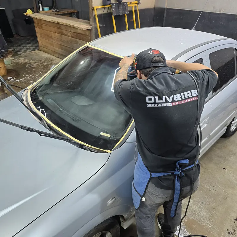 Trabalho no para-brisa de um carro prata, com o vidro fitado nas bordas