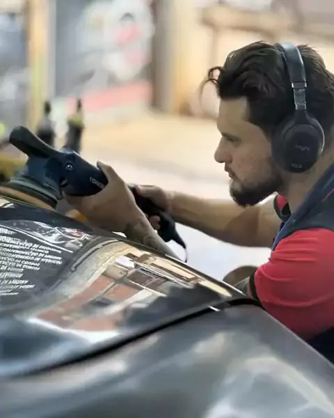 Gilberto polindo o capô de um carro escuro