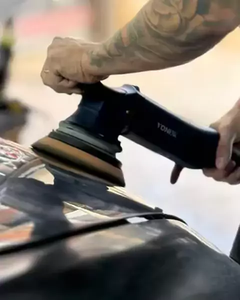 Boina de polimento em contato com o capô preto de um carro